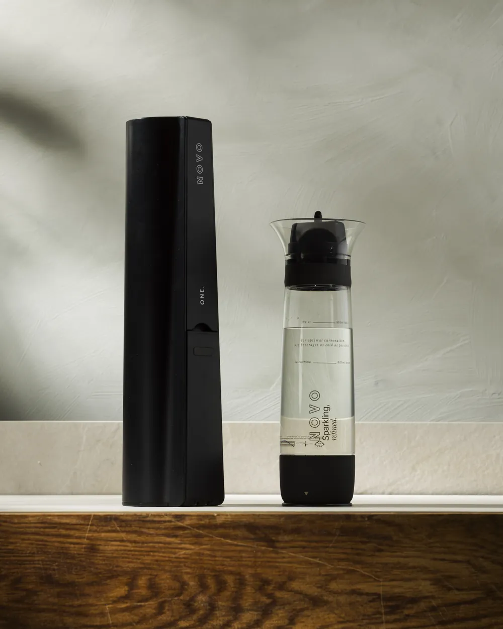 NOVO One in Antracite Black beside its bottle on a stone countertop
