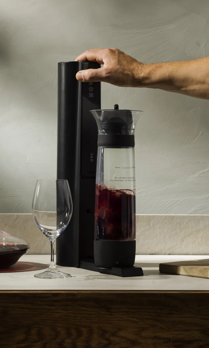NOVO One in Antracite Black carbonating red wine, beside a decanter and an artichoke